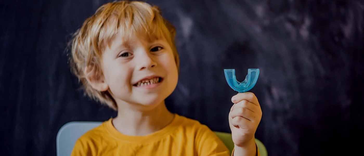 Child holding up mouthguard used as part of non surgical bite correction plan