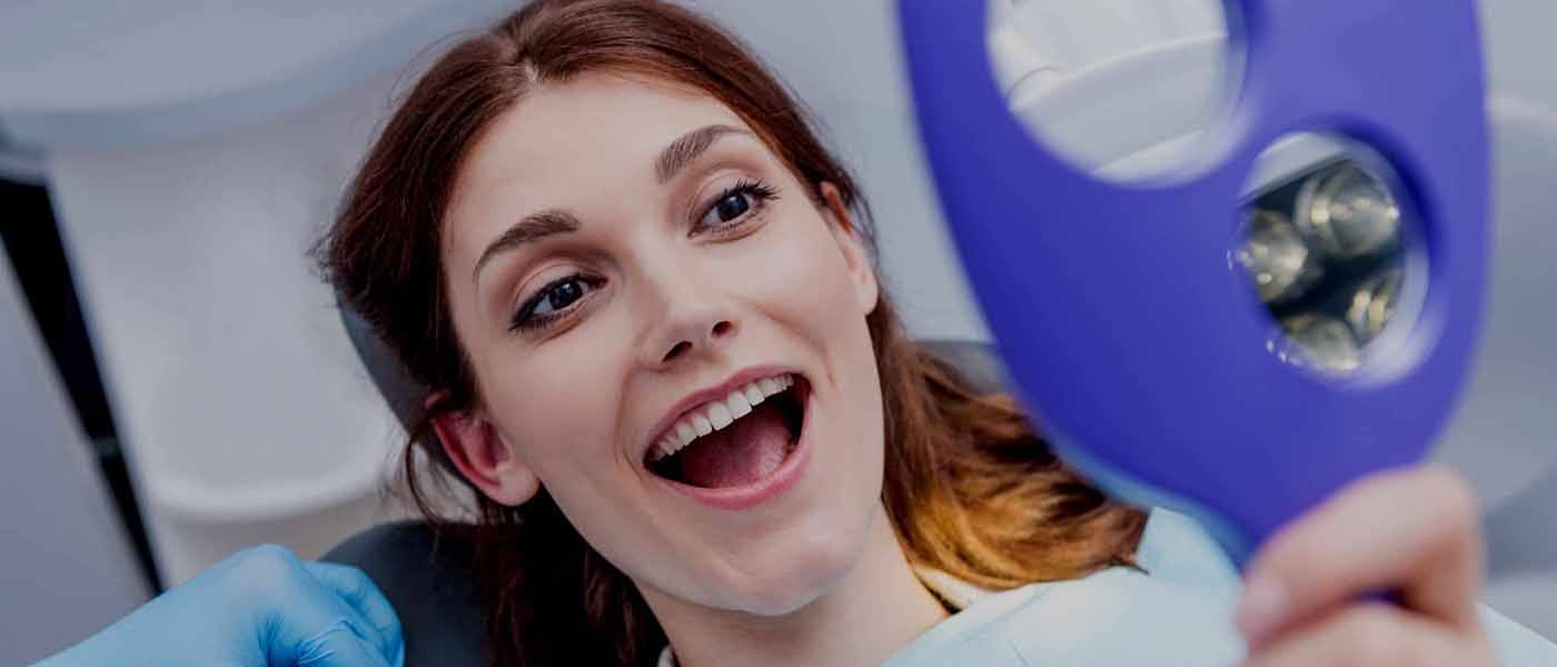 Woman smiling in the mirror after orthodontic treatment