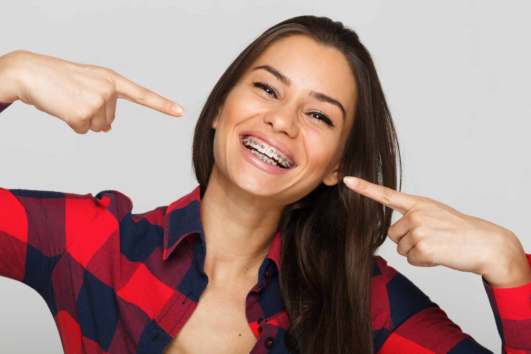 woman pointing to her metal braces