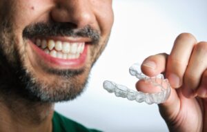 Man smiling while putting in his Invisalign tray